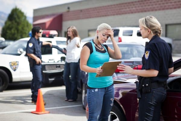 A woman explaining the events of her car accident to a police officer.