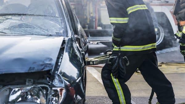 An EMS worker uses the jaws of life on a wrecked car.