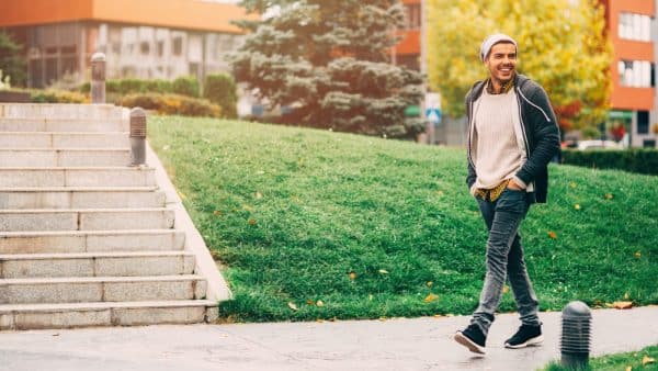 Young Man Walking Alone On A Sidewalk Stock Photo